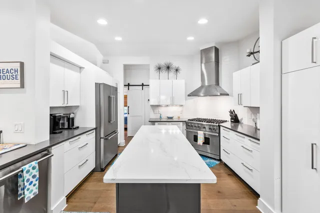 a large kitchen with stainless steel appliances granite countertop a stove top oven a refrigerator a sink and dishwasher