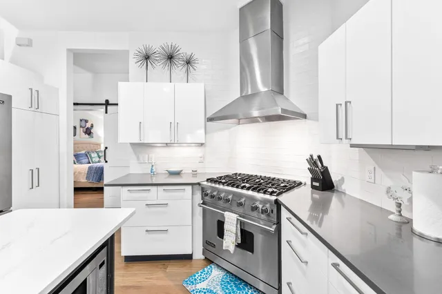 a kitchen with stainless steel appliances a white cabinets and a stove top oven