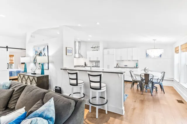 a kitchen with stainless steel appliances kitchen island granite countertop a refrigerator a stove a dining table and chairs with wooden floor