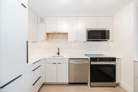 a kitchen with white cabinets stainless steel appliances and sink