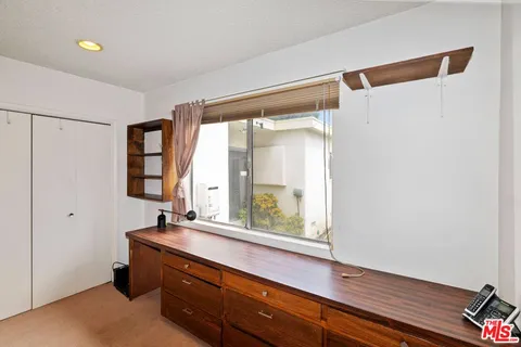 a room with a large window and a potted plant on the wall