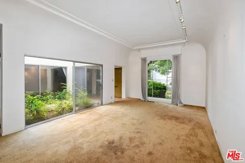 a view of a big room with windows and plants