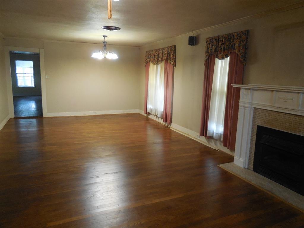 609 West Main Street Ranger, TX 76470 - Photo 3 of 29 an empty room with wooden floor fireplace and windows