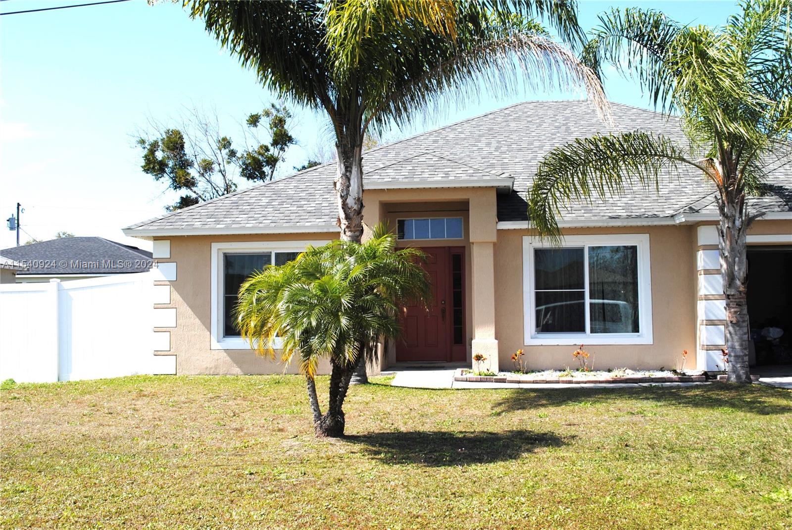 a front view of house with small garden and palm trees