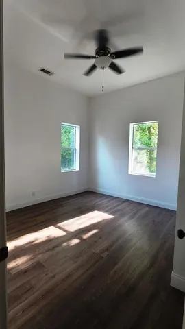 a view of an empty room with wooden floor and a window