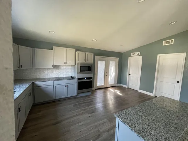 a kitchen with granite countertop a stove and cabinets