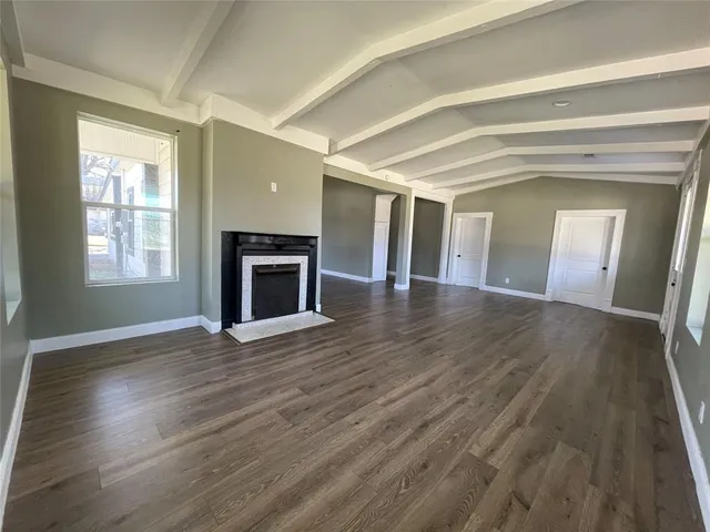 an empty room with wooden floor fireplace and windows