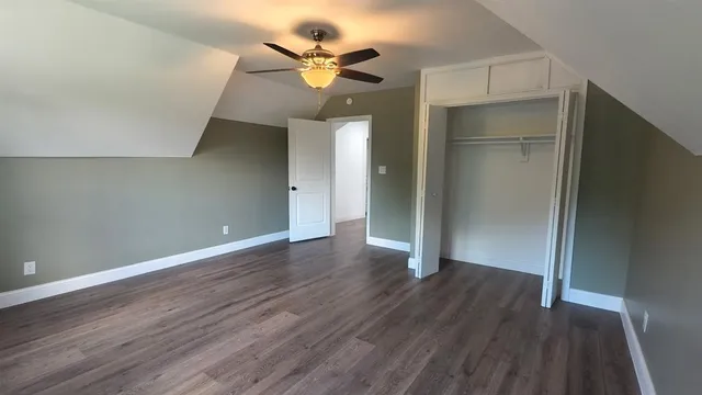 an empty room with wooden floor and a ceiling fan
