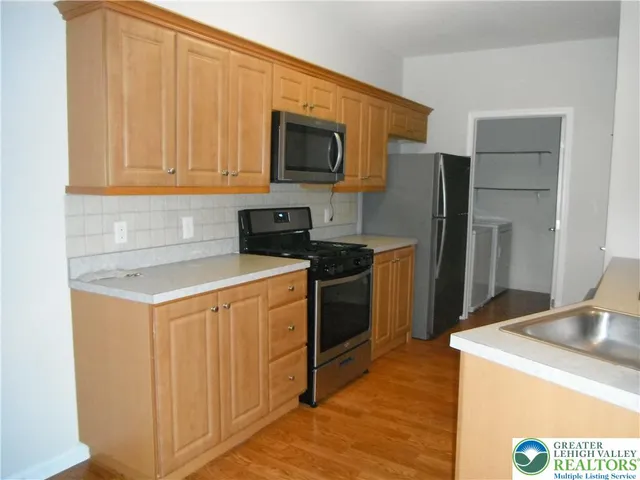 a kitchen with stainless steel appliances granite countertop a refrigerator a stove a sink and a microwave