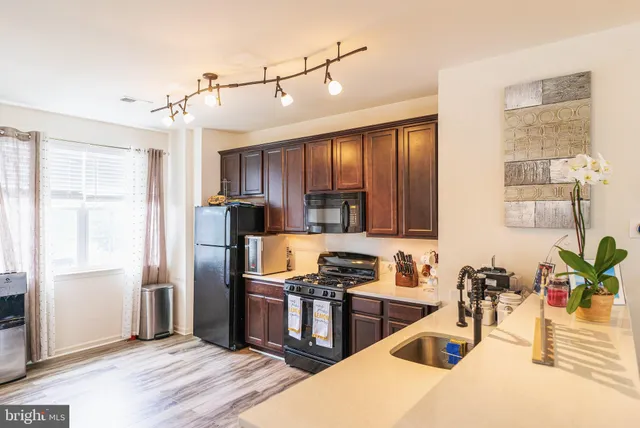 a kitchen with granite countertop a refrigerator a stove and a sink with wooden floor