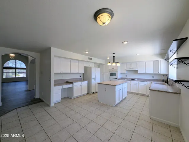an empty room with wooden floor chandelier and windows