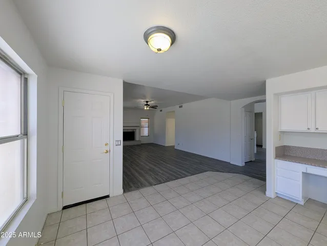 an empty room with wooden floor chandelier fan and windows