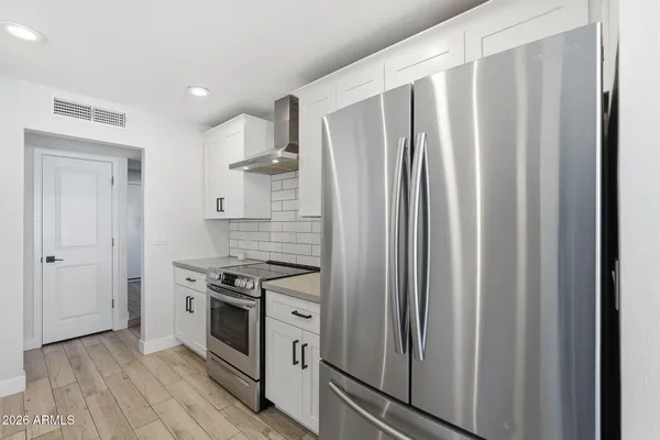 a kitchen with stainless steel appliances a refrigerator a stove a sink dishwasher and a dining table with wooden floor