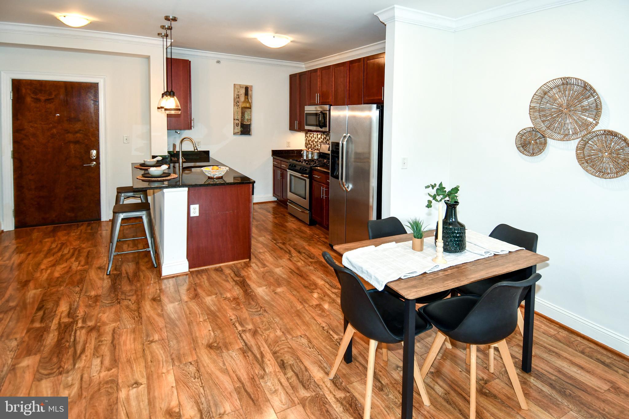 6301 Edsall Road, Unit 115 Alexandria, VA 22312 - Photo 7 of 37 a kitchen with stainless steel appliances kitchen island granite countertop a refrigerator a stove a sink dishwasher and a dining table with wooden floor