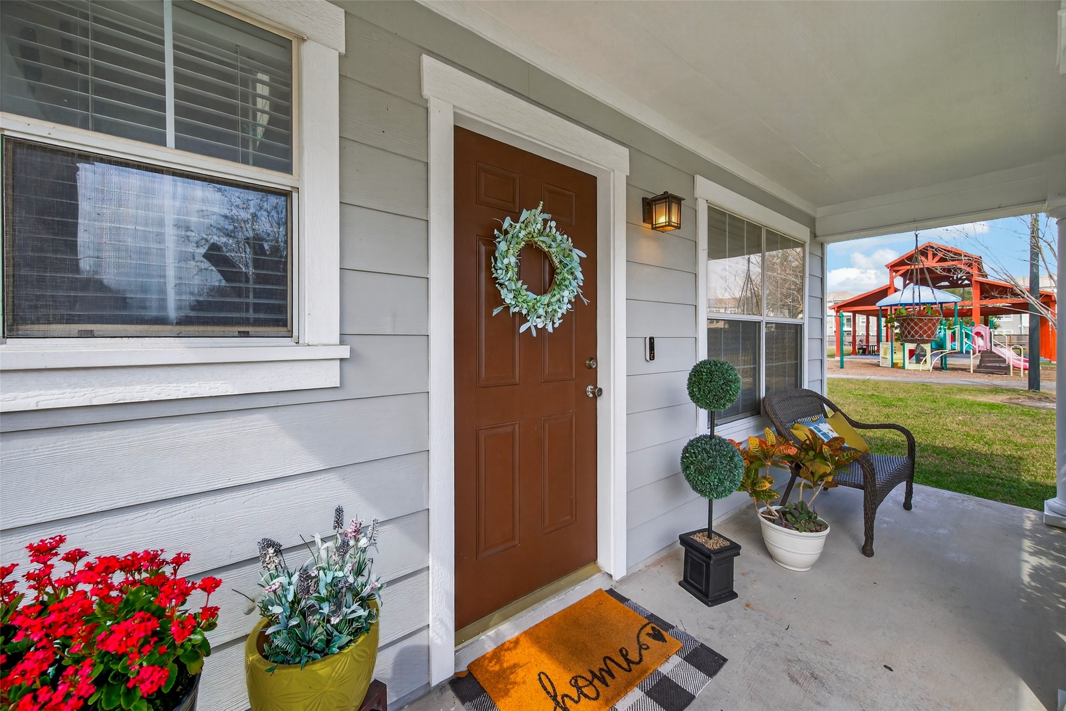 9902 Victoria Point Lane Houston, TX 77075 - Photo 2 of 35 Charming front porch with a welcoming wreath on the door and cozy seating. The space is adorned with vibrant plants, and there's a view of a nearby playground, making it ideal for families.