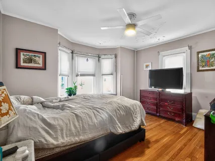 a spacious bedroom with a bed a dresser and next to a window