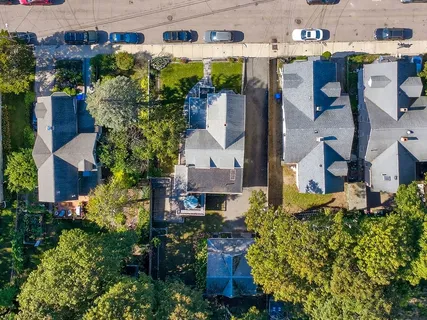 an aerial view of residential houses with outdoor space and trees