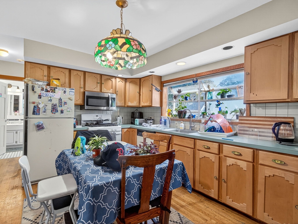 148 Beaver Street Boston, MA 02136 - Photo 9 of 25 a kitchen with stainless steel appliances granite countertop a sink dishwasher a microwave oven with a dining table and chairs with wooden floor