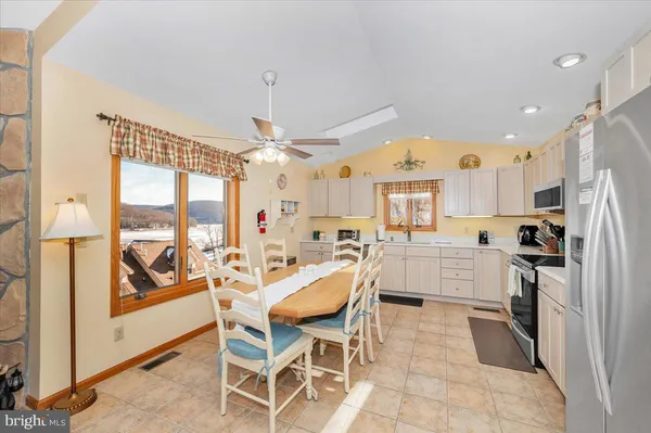 a view of a kitchen with kitchen island granite countertop appliances cabinets and a dining table