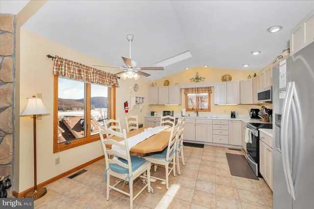 a view of a kitchen with kitchen island granite countertop appliances cabinets and a dining table