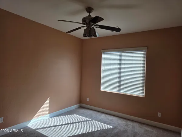 an empty room with a window and a fan