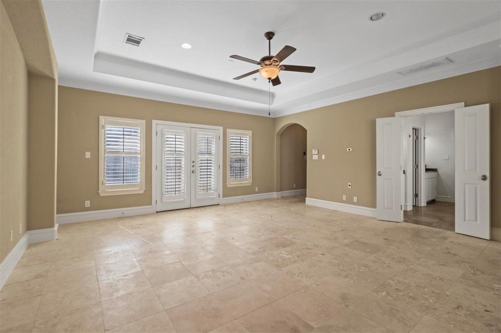 4516 Gilbert Avenue Dallas, TX 75219 - Photo 17 of 29 Owner's suite bedroom with access to outside, a ceiling fan, arched walkways, a raised ceiling, and french doors