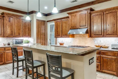a kitchen with stainless steel appliances granite countertop wooden cabinets a stove a sink and a microwave