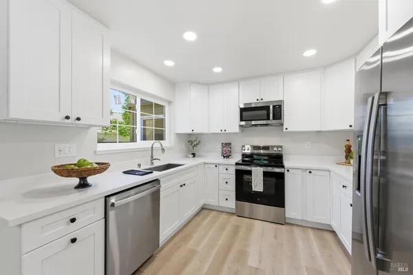 a kitchen with stainless steel appliances granite countertop a stove a refrigerator a stove a sink a dining table and chairs with wooden floor