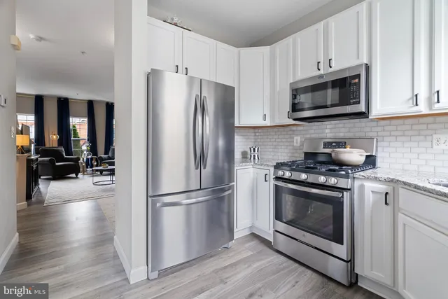 a kitchen with cabinets stainless steel appliances and wooden floor