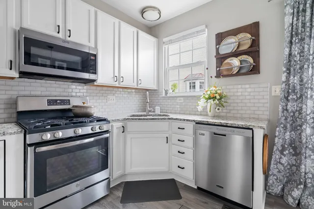 a kitchen with stainless steel appliances granite countertop a stove a microwave and wooden cabinets