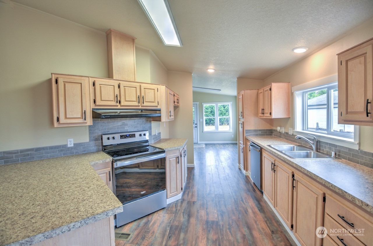 19212 Old Ranch Lane Southwest Rochester, WA 98579 - Photo 11 of 33 a kitchen with wooden floor a stove a sink and a microwave