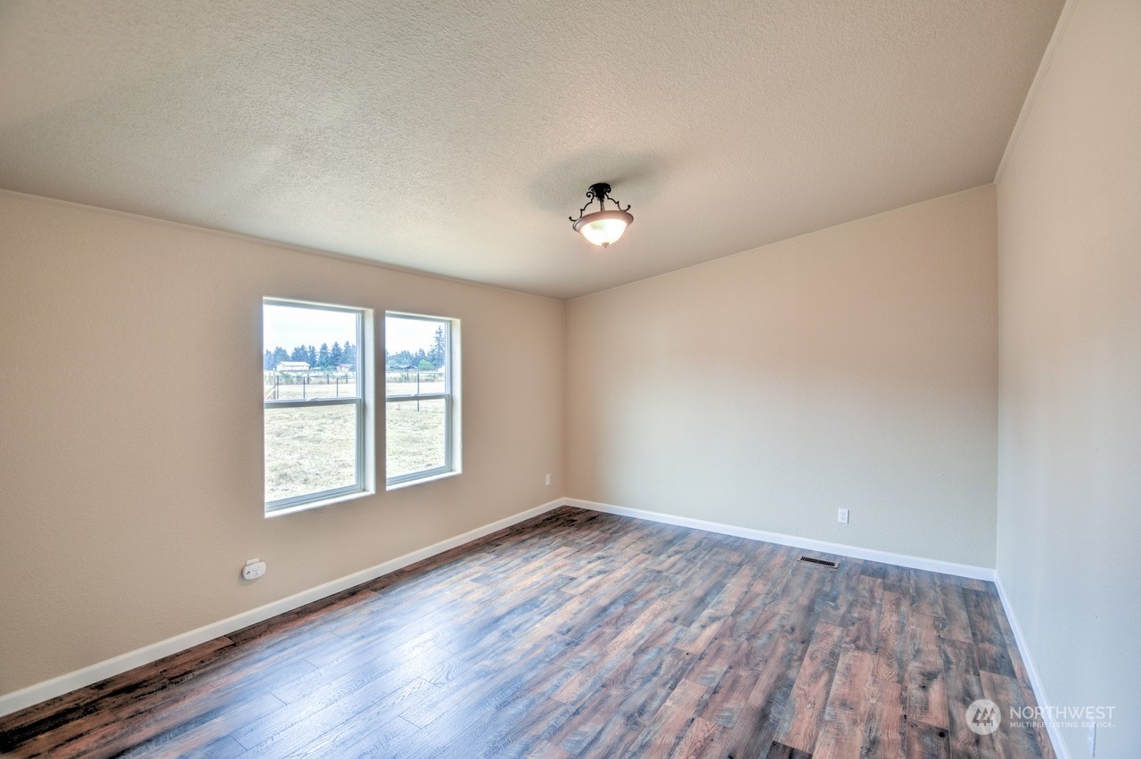 19212 Old Ranch Lane Southwest Rochester, WA 98579 - Photo 13 of 33 an empty room with wooden floor and windows
