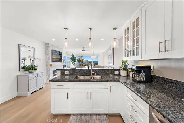 a kitchen with stainless steel appliances granite countertop a refrigerator a stove and a sink with wooden floor