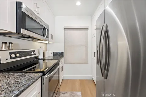 a kitchen with stainless steel appliances granite countertop a refrigerator a stove and a sink with wooden floor