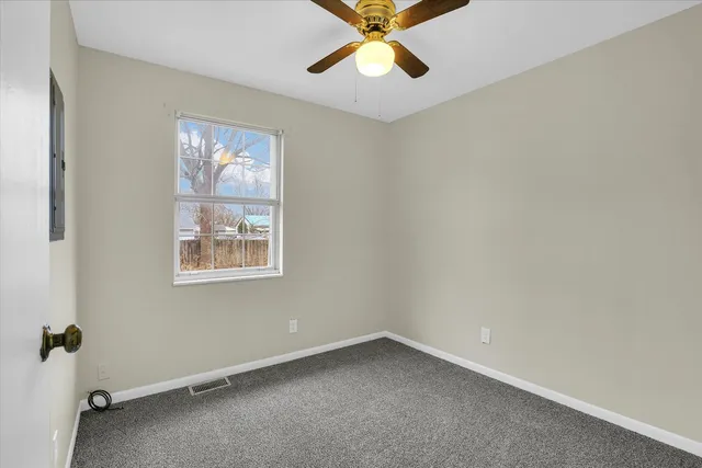 an empty room with windows and fan