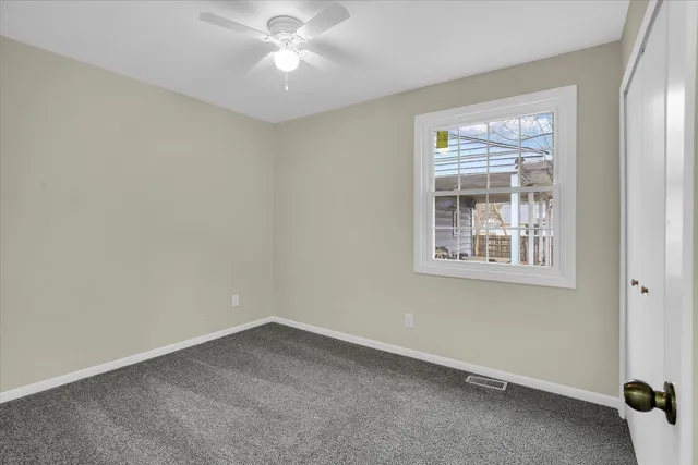 an empty room with a window and a fan