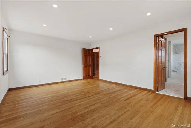 a view of an empty room with wooden floor and closet