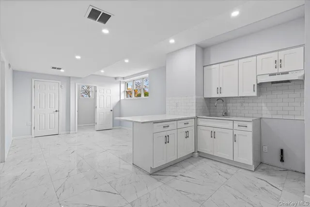 a large white kitchen with granite countertop white cabinets and stainless steel appliances