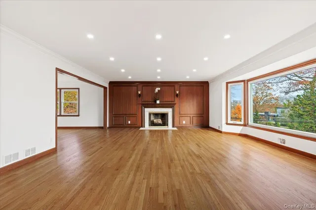 a view of an empty room with a window and wooden floor