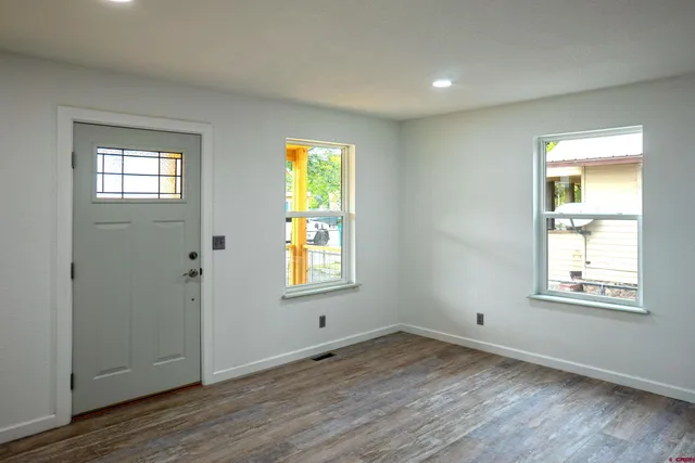 an empty room with wooden floor and windows