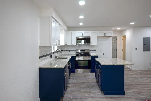 a kitchen with kitchen island granite countertop a sink stove and refrigerator
