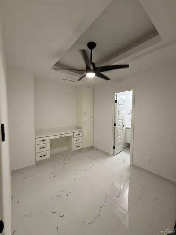 1825 Sunset Drive Mission, TX 78572 - Photo 2 of 12 Unfurnished bedroom featuring built in desk, light marble finish flooring, a ceiling fan, connected bathroom, and a raised ceiling