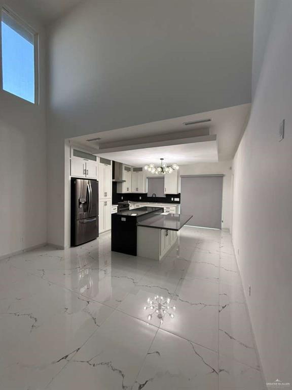 1825 Sunset Drive Mission, TX 78572 - Photo 4 of 12 Kitchen featuring a high ceiling, hanging lights, white cabinets, a kitchen island, and light marble finish floors