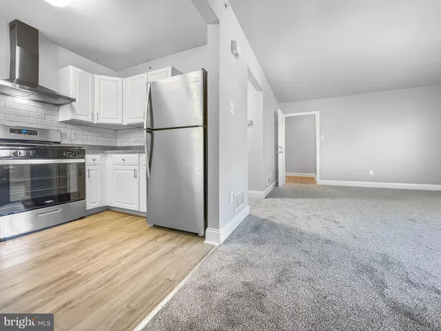 a kitchen with granite countertop a refrigerator and a stove top oven