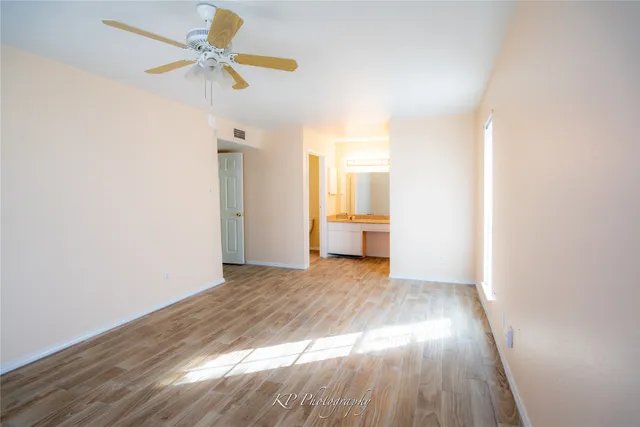 a view of empty room with wooden floor and fan