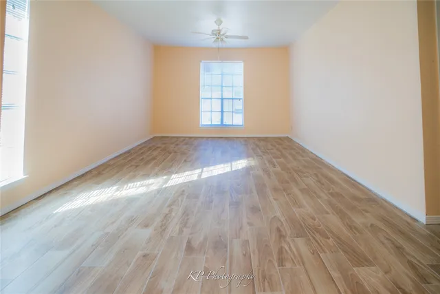 an empty room with wooden floor exposed radiator and windows