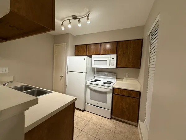 a kitchen with a sink a refrigerator and white cabinets
