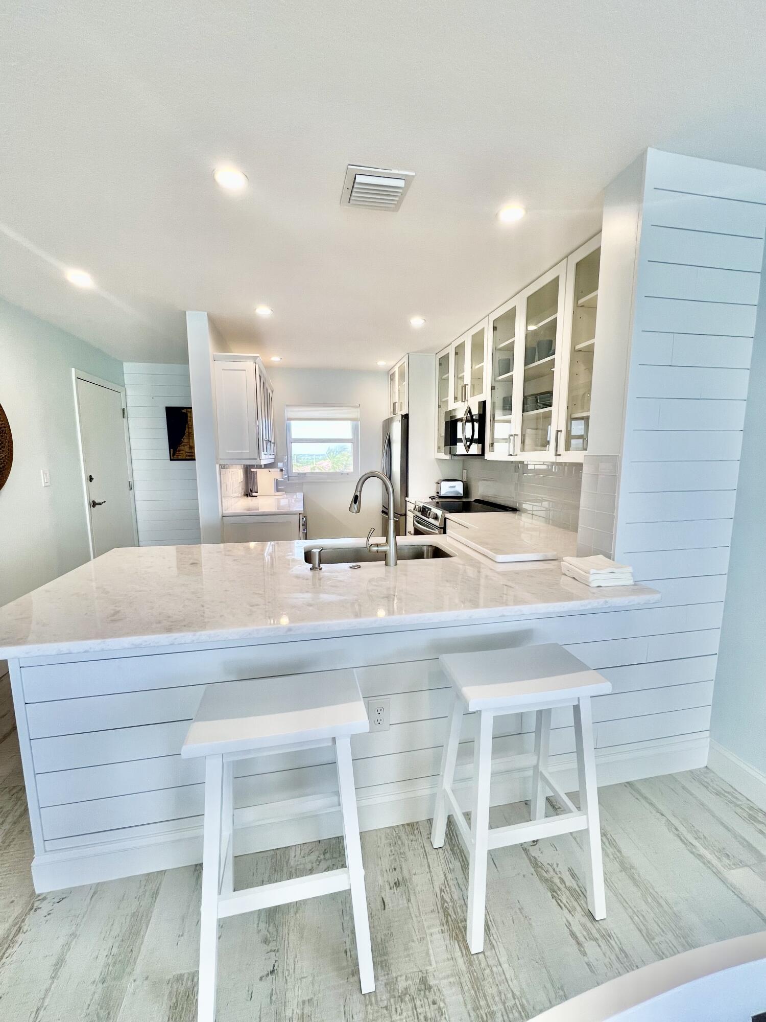 7410 South Ocean Drive, Unit 505 Jensen Beach, FL 34957 - Photo 7 of 33 a kitchen with kitchen island granite countertop wooden cabinets and dining table
