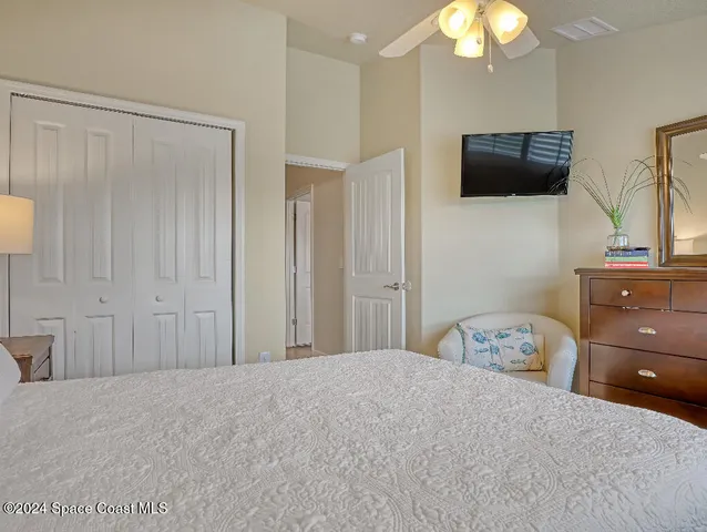 a bedroom with a bed and flat tv screen on the dresser