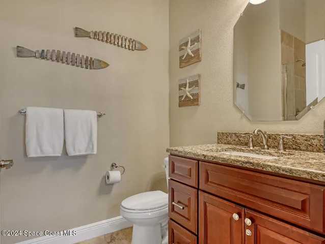 a bathroom with a granite countertop toilet sink and mirror